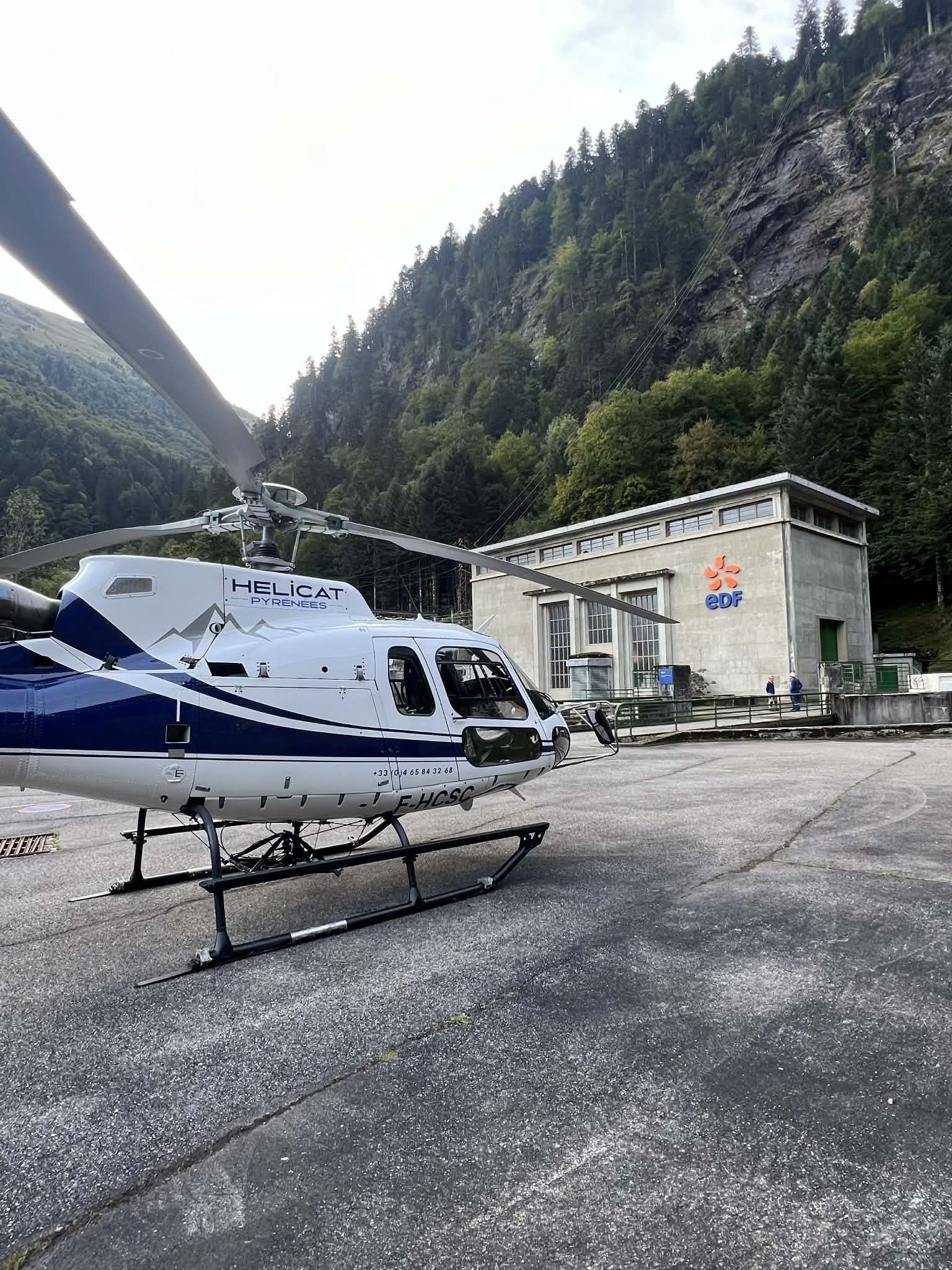 AS350 Helicat Pyrénées posé devant une centrale hydroélectrique EDF en vallée