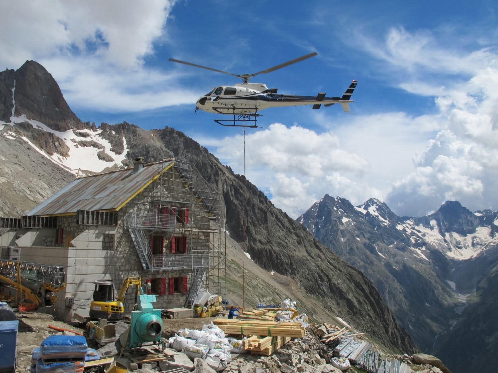 AS350 Helicat livrant des matériaux sur un refuge de haute montagne en travaux