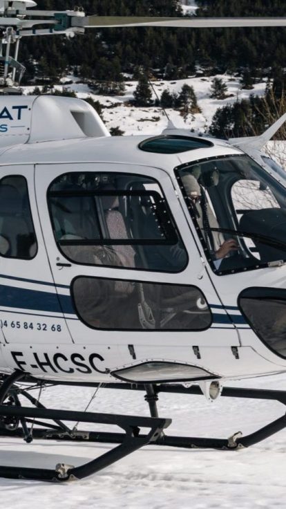 Helicopter on snow, ski resort and mountains in the background