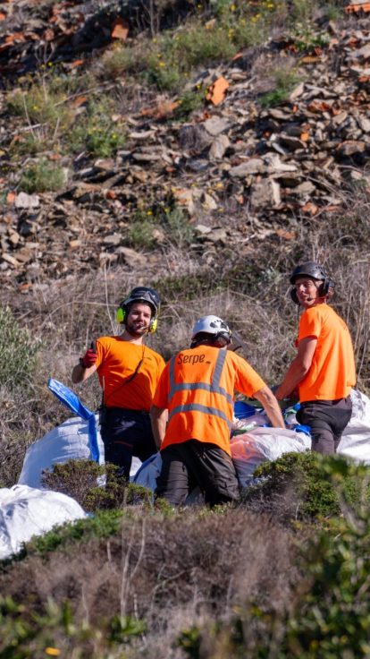 Trois techniciens posant devant des big bags sur un versant rocheux