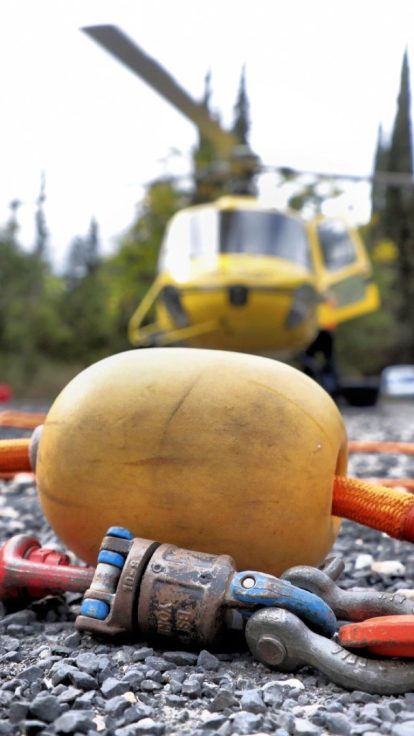 Hélicoptère posé sur une route de montagne, équipe préparant élingues et big bags