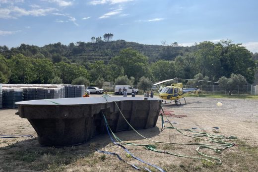 Hélicoptère transportant une charge suspendue au-dessus d'un village