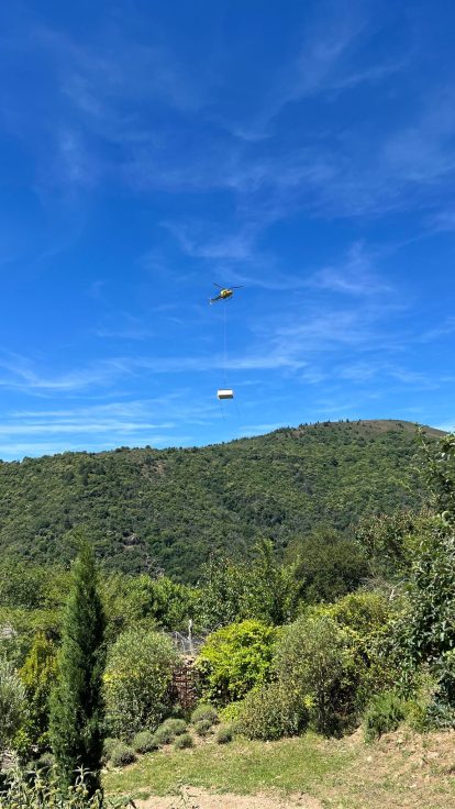 Hélicoptère transportant une piscine au-dessus d'un jardin