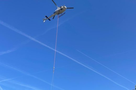 Hélicoptère transportant une structure de pylône en treillis sous double élingue